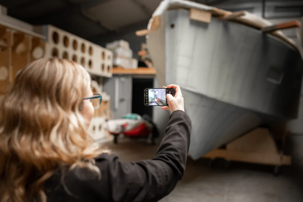 Persoon fotografeert een bootonderdeel in de werkplaats