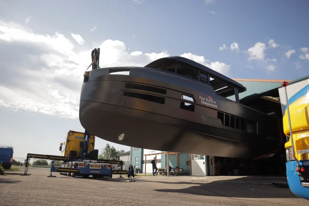 Dark motor yacht hull being lifted outdoors