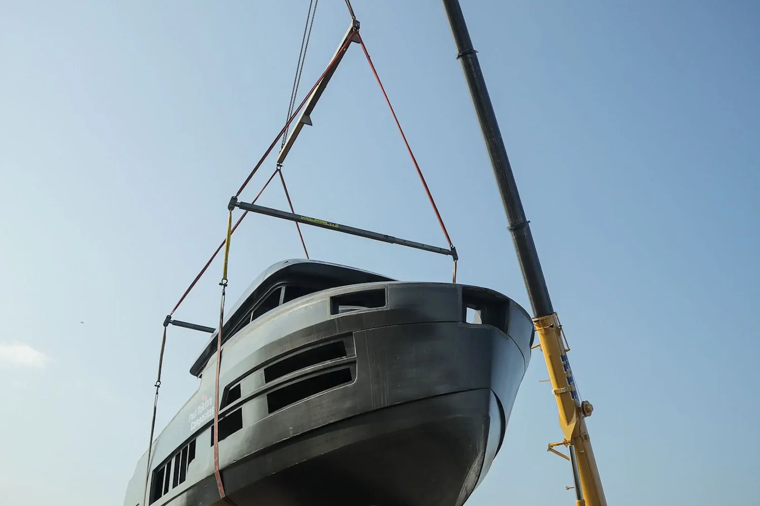 Yacht suspended from lifting straps above the quay