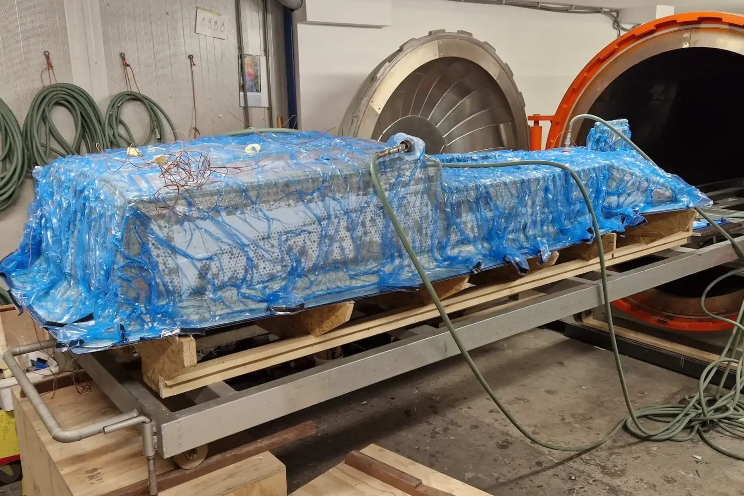 Boat component under blue vacuum film on a work trestle