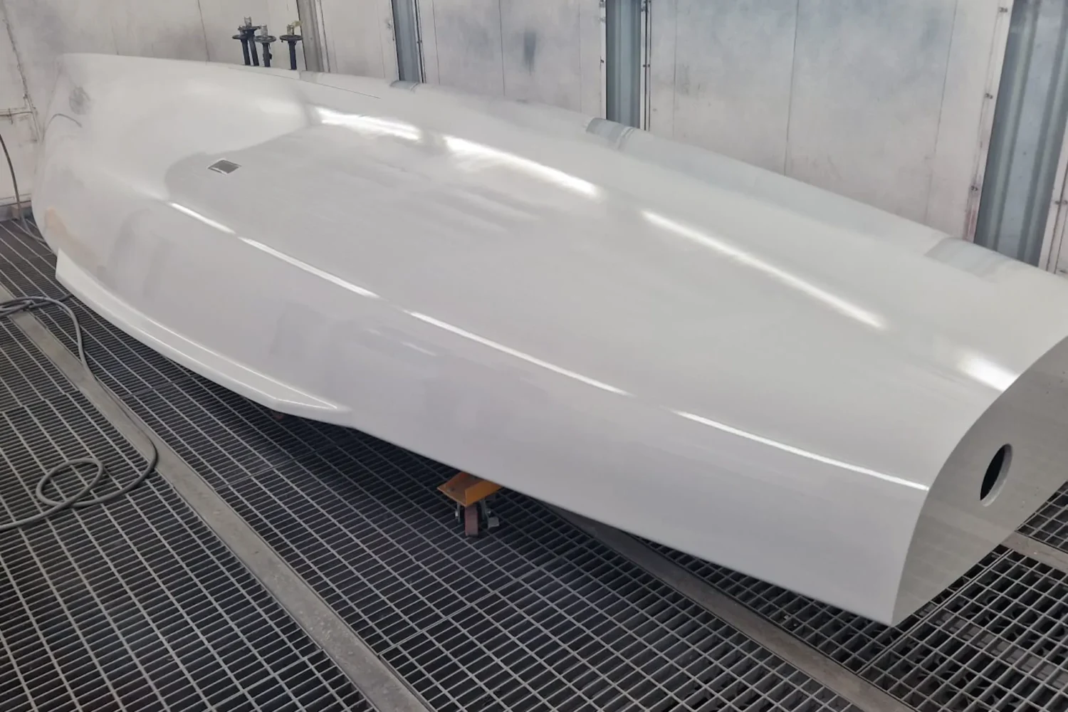 White boat hull viewed from the side in a spray booth