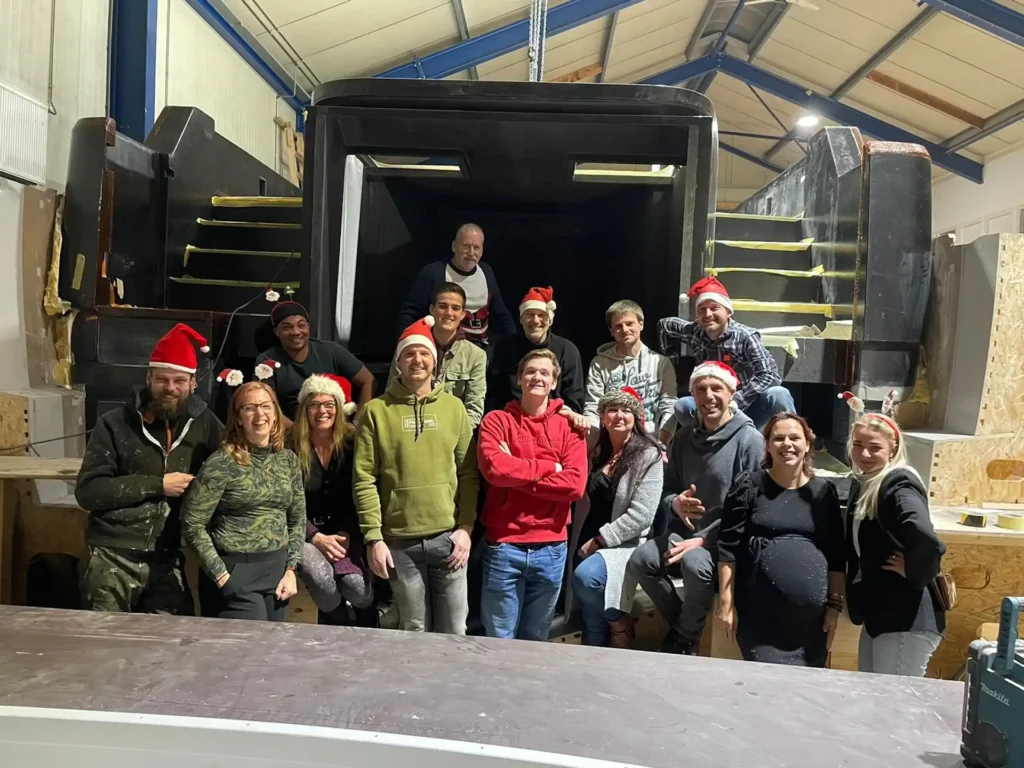 Group photo in front of a boat hull in the workshop