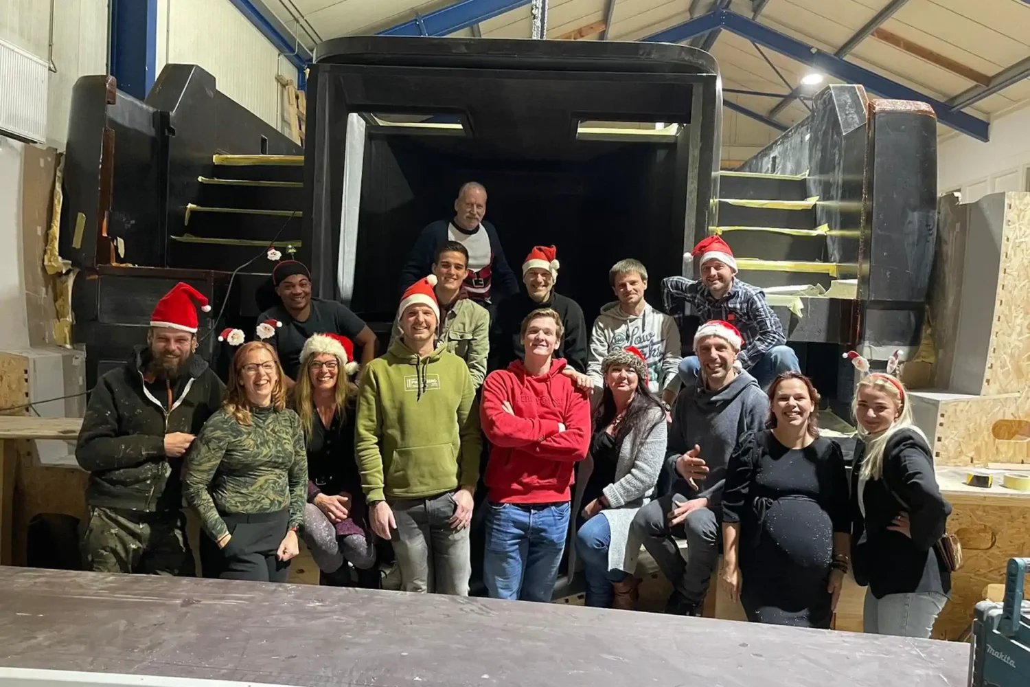 Group photo in front of a boat hull in the workshop