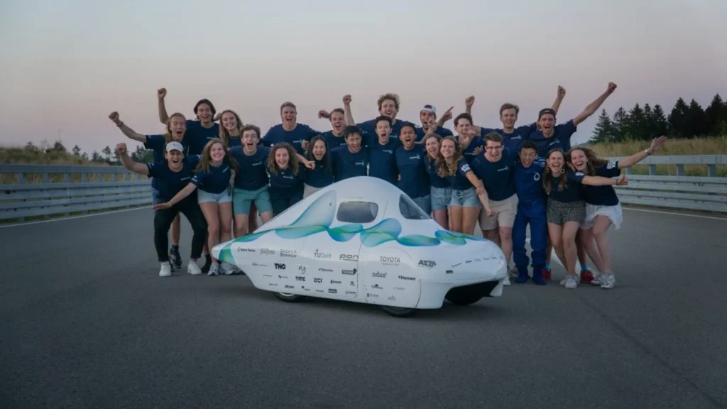 Team posing with a white solar-powered car
