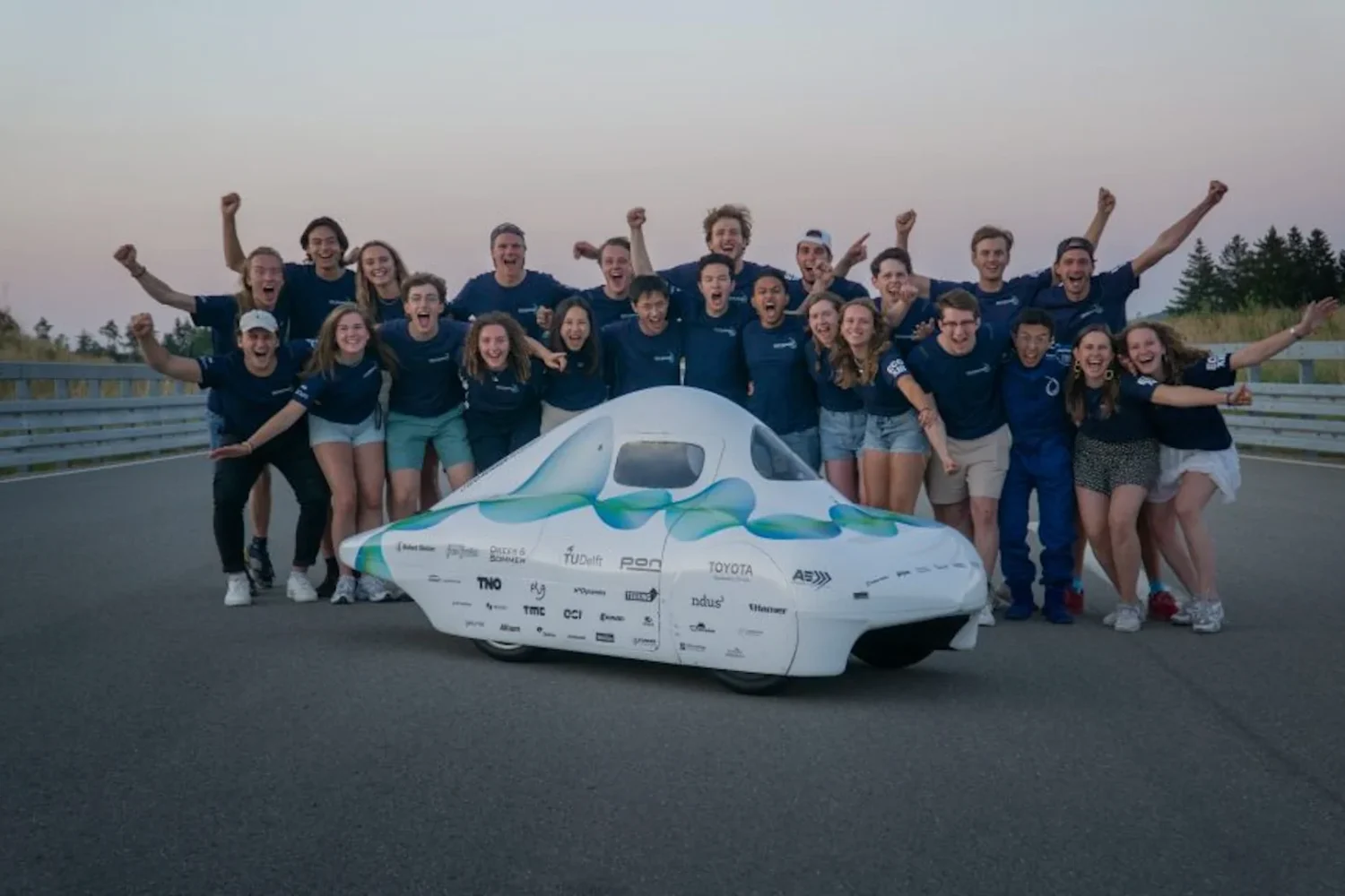 Team posing with a white solar-powered car