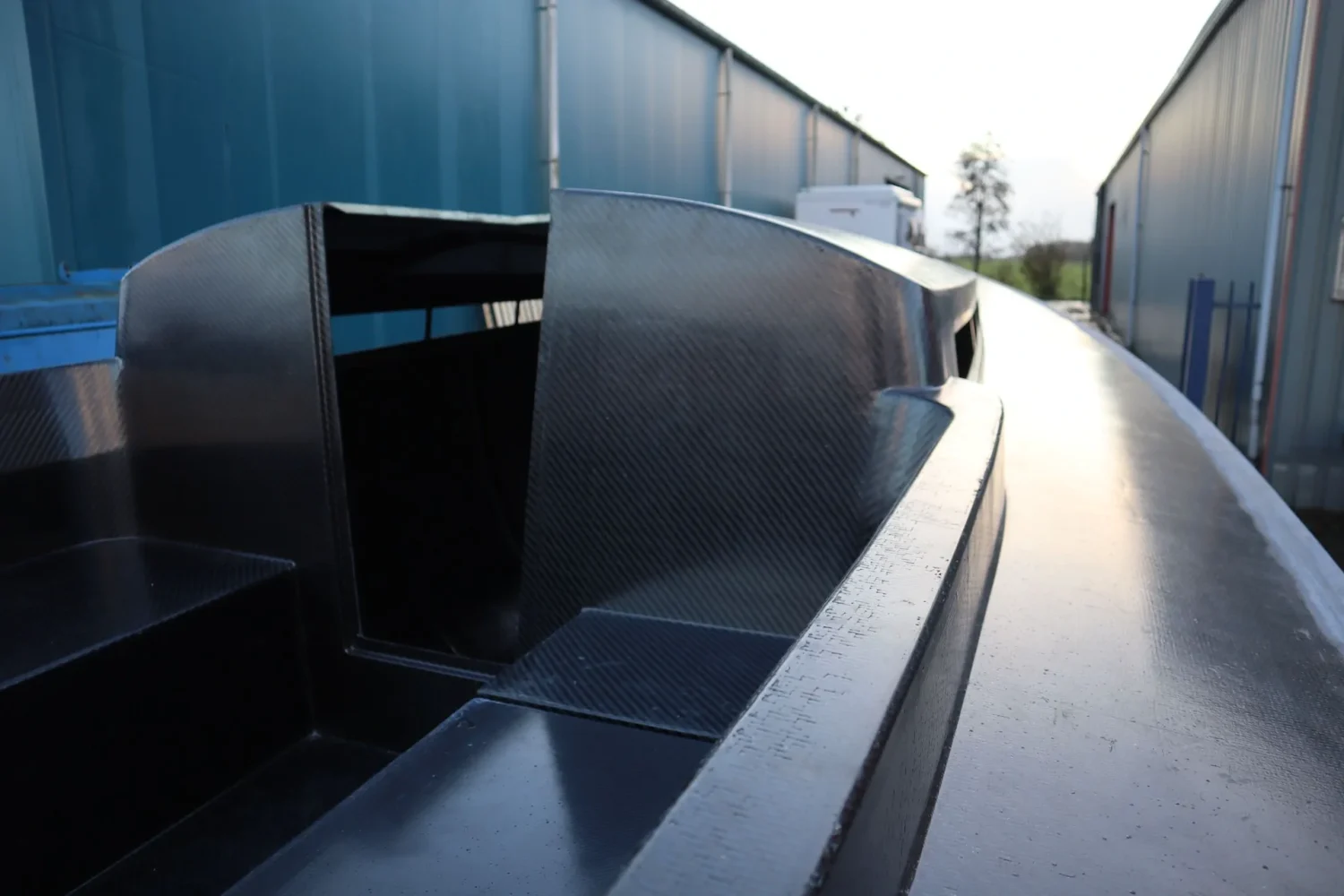 Dark boat hull outside between two workshop buildings