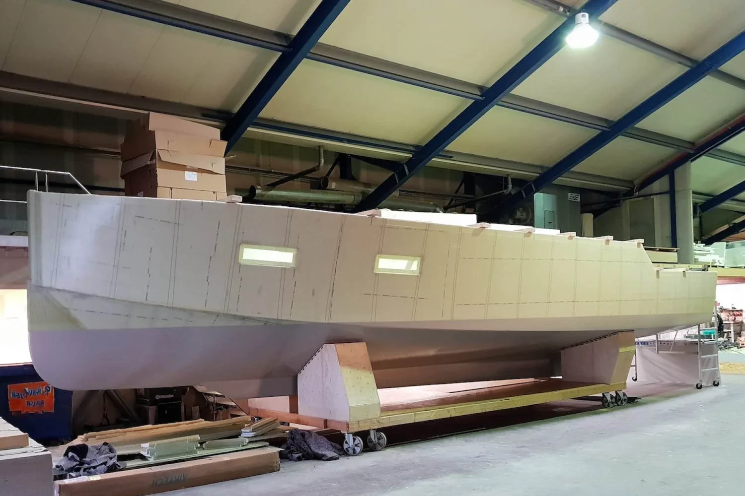 Light-colored boat hull on supports in the workshop