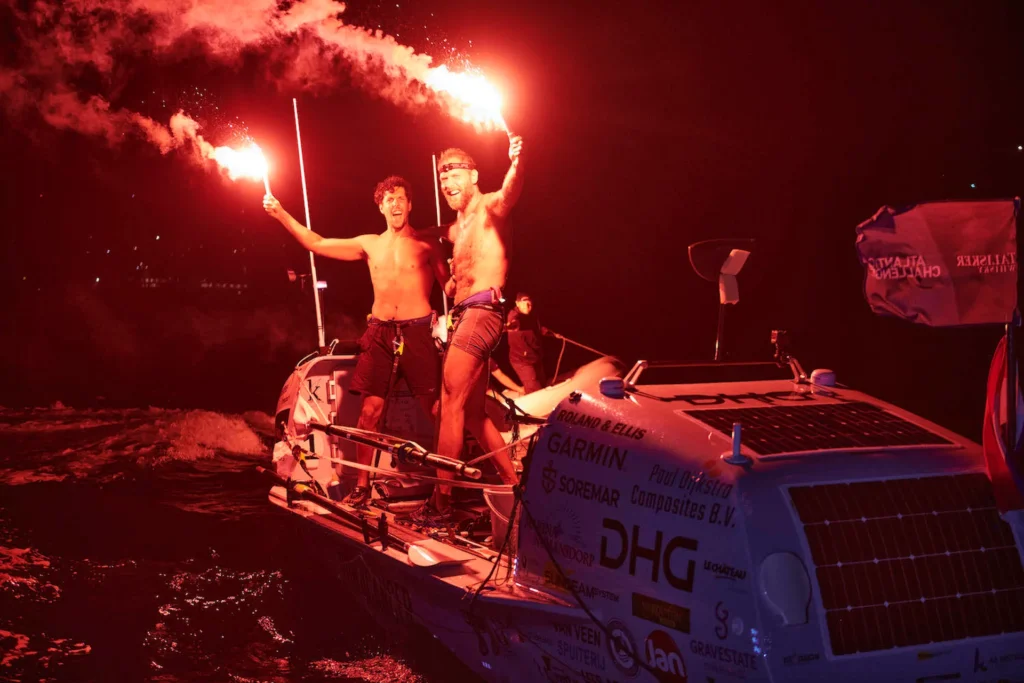Rowers celebrate their arrival with red flares