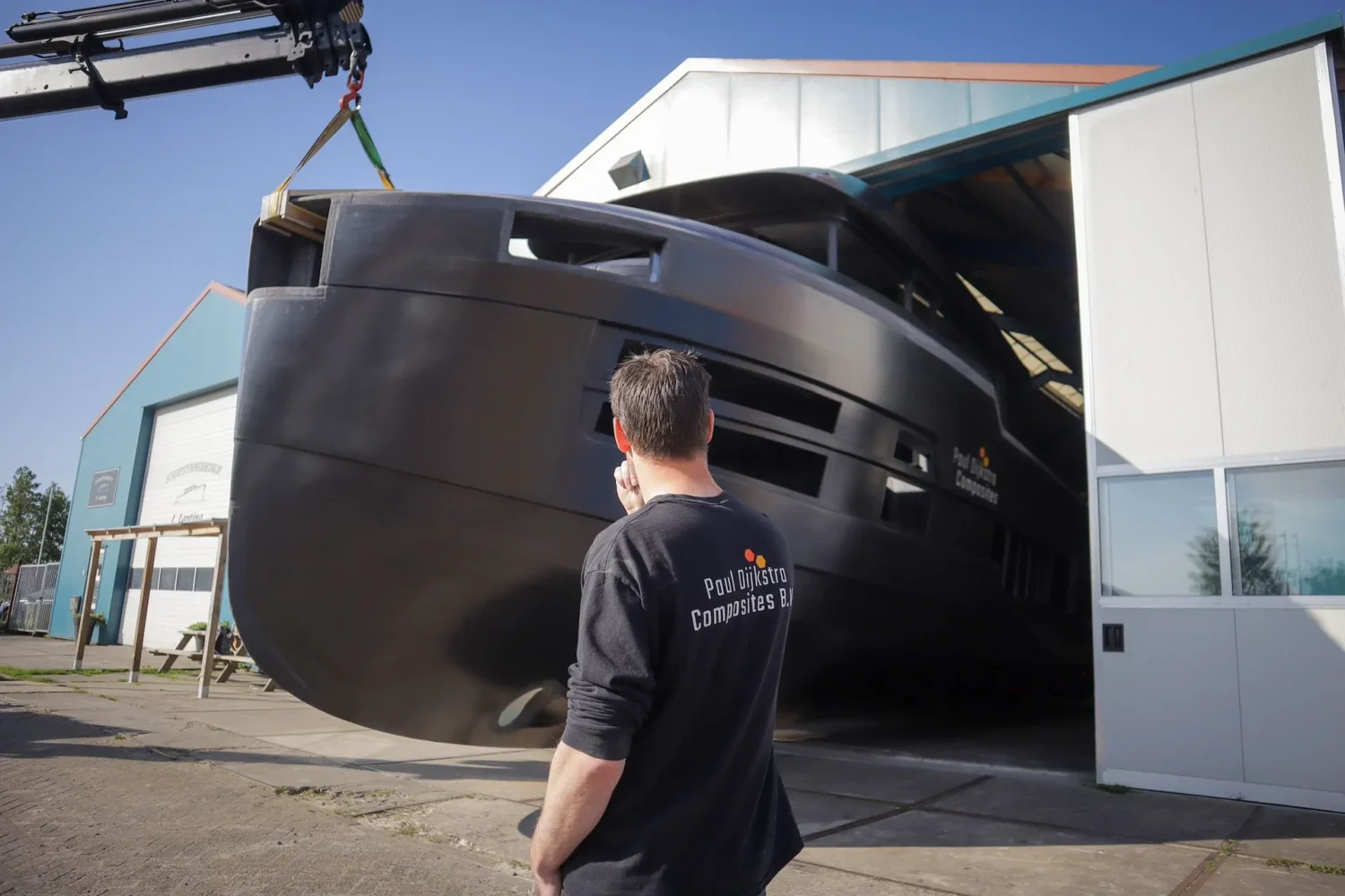 Employee looking at a boat hull by the workshop door