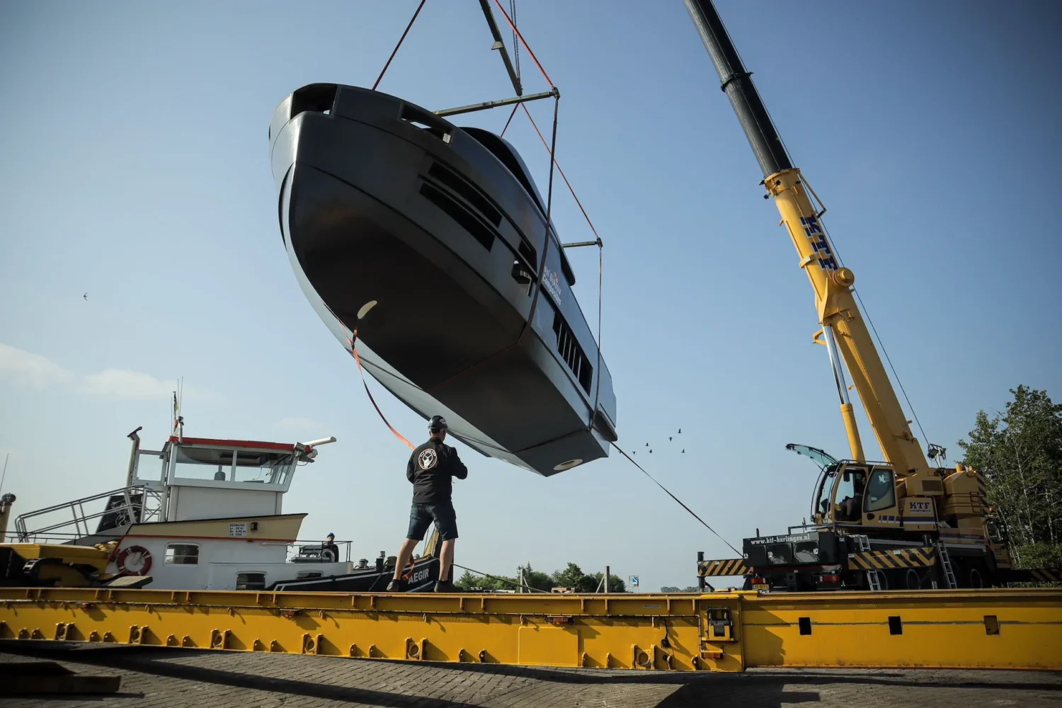 Boat hull being lifted by crane above a pontoon