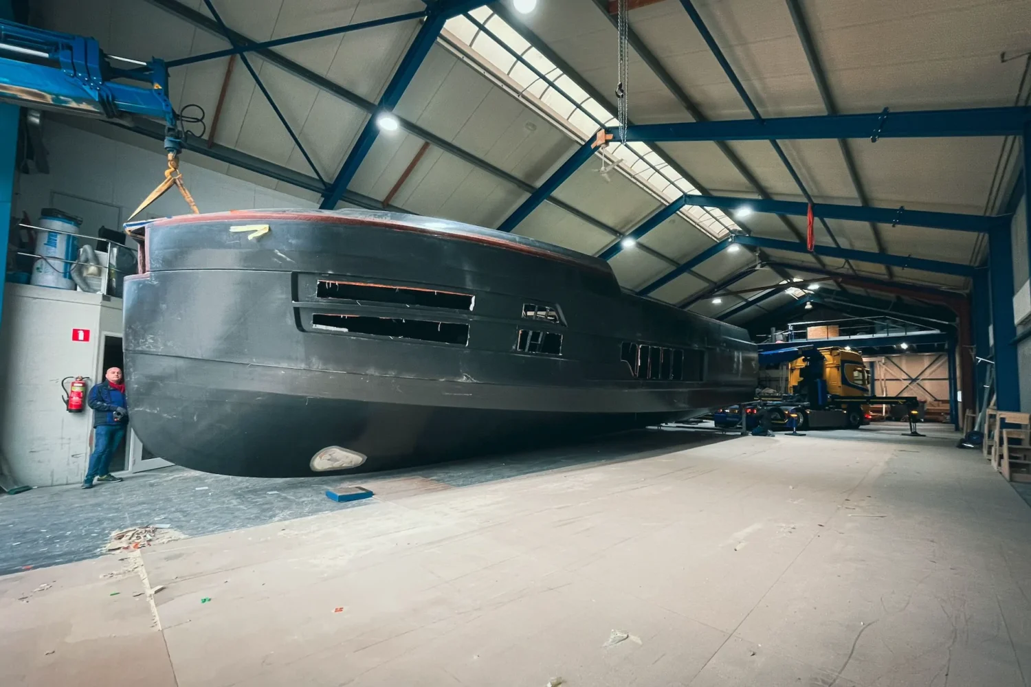 Dark yacht hull beside work platforms