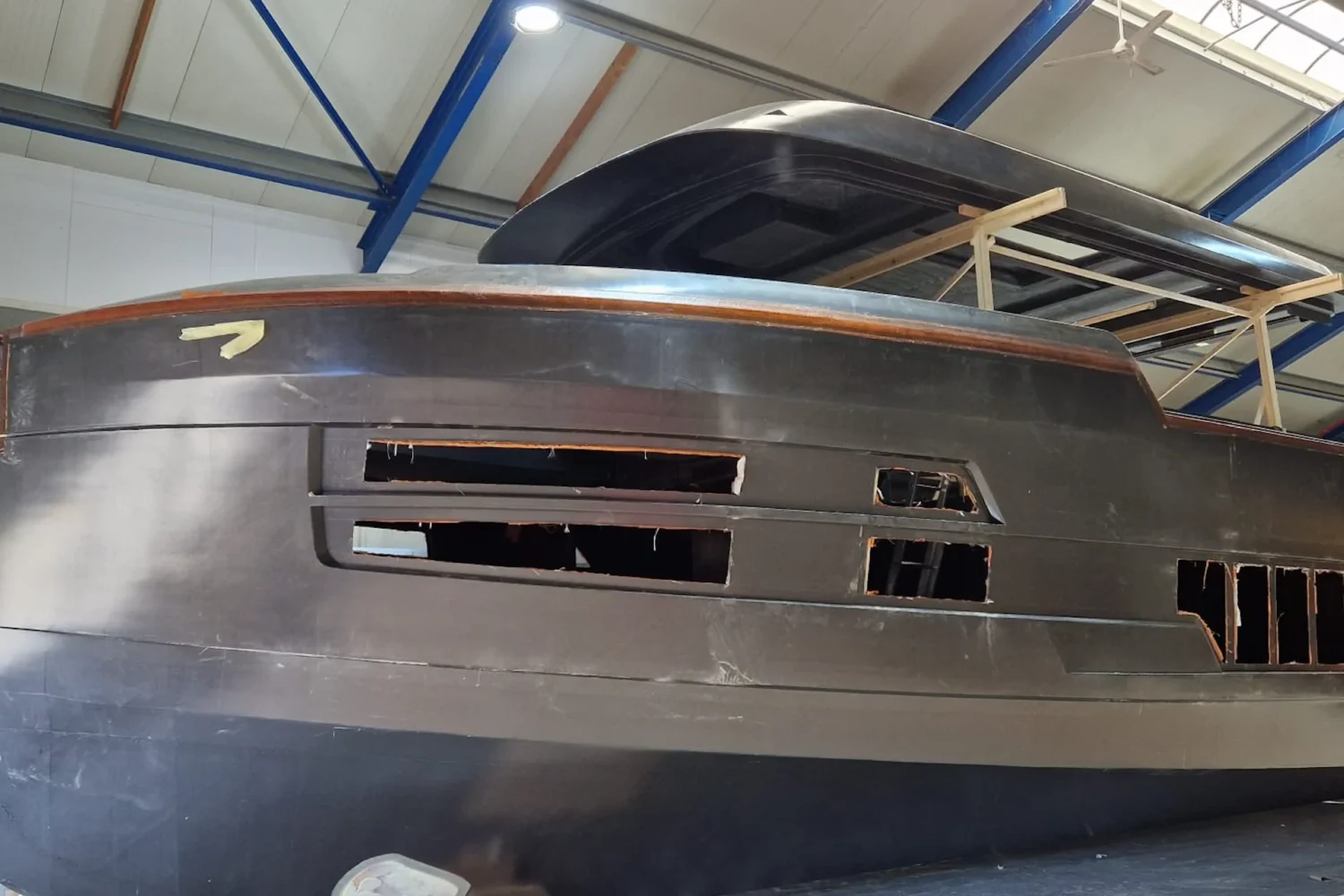 Side view of a dark yacht hull in the workshop