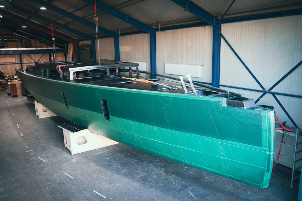 Green boat hull on supports inside the workshop