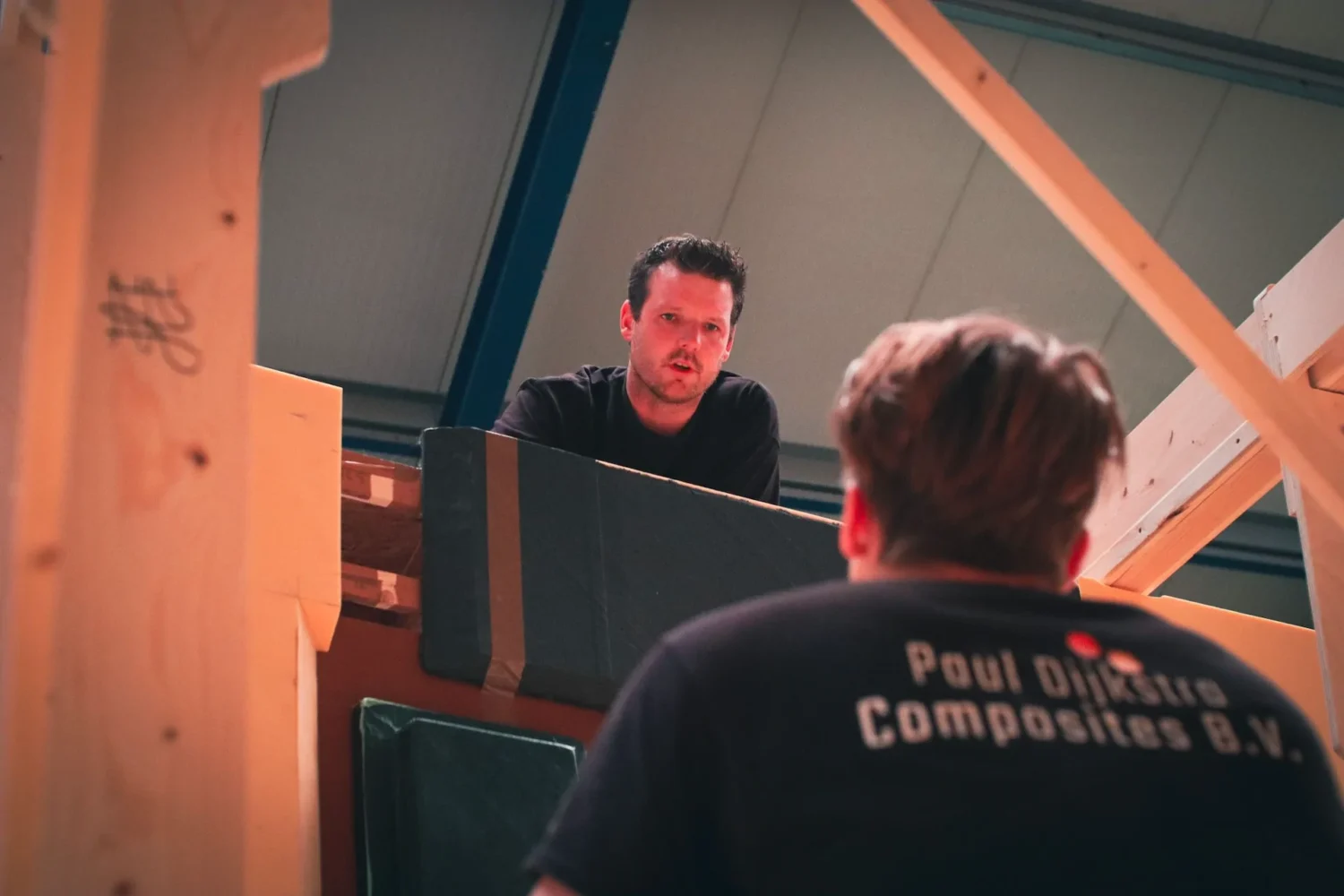 Employees consulting beside a wooden construction frame