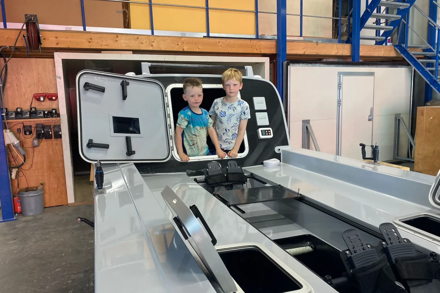 Two people beside a boat deck in the workshop