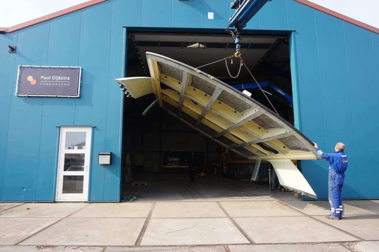 Large boat component being tilted by the workshop door