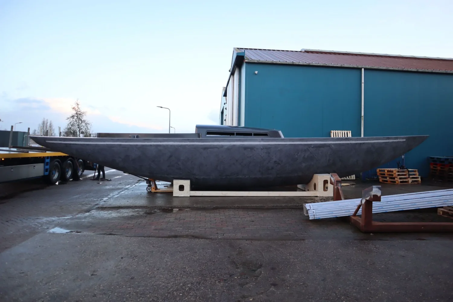 Long boat hull outside the workshop