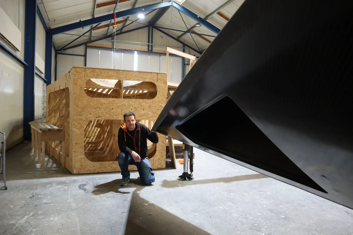 Employee beside a dark boat hull in the workshop