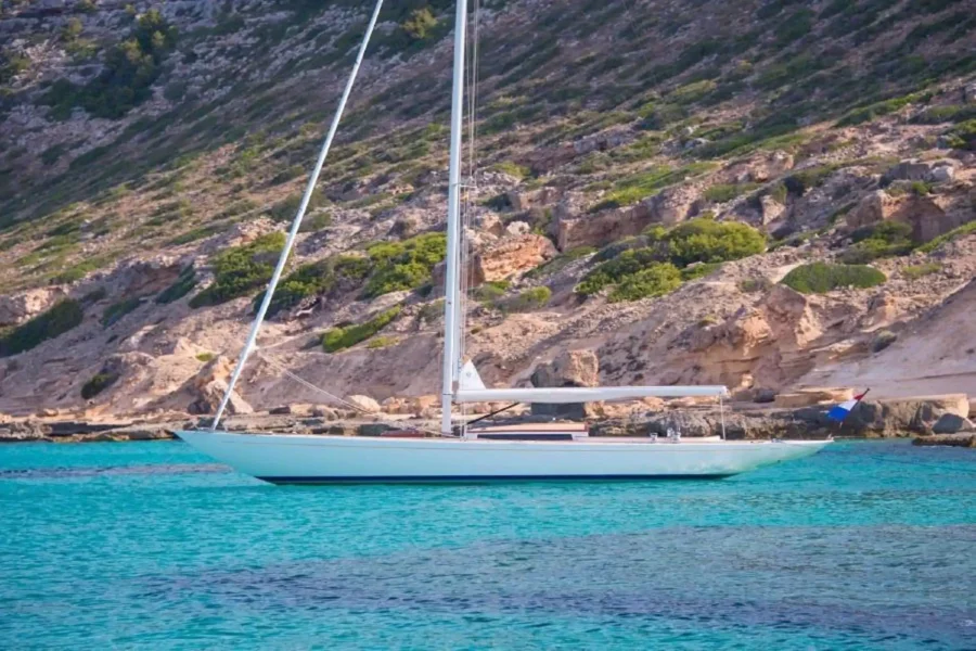 Sailing yacht anchored off a rocky coast
