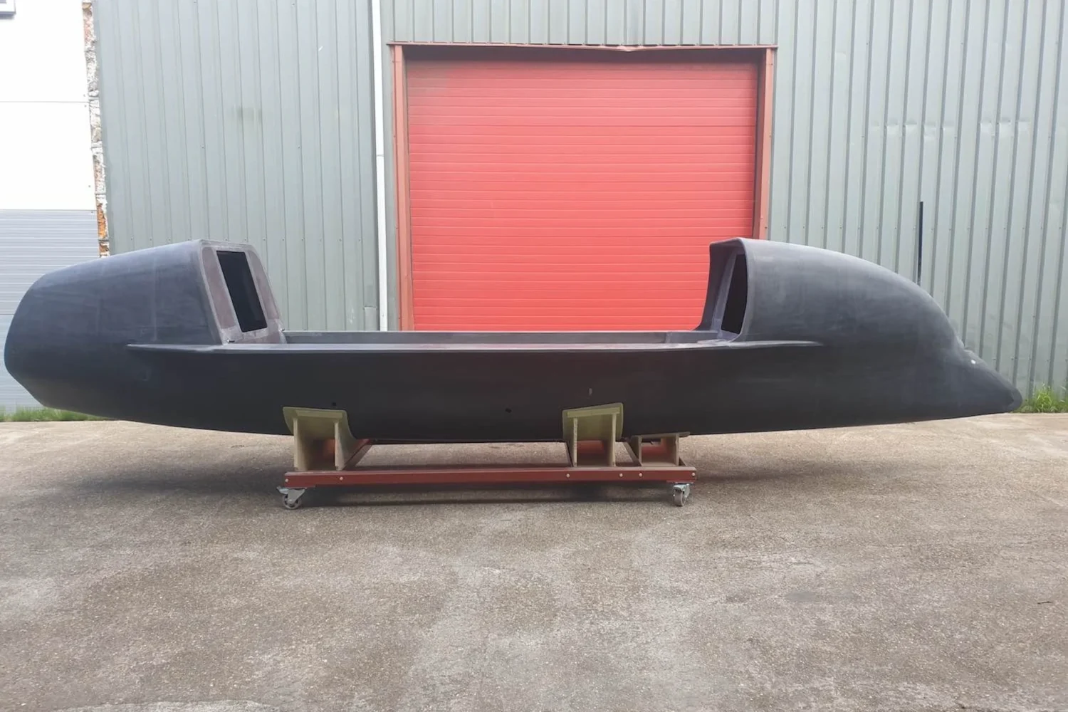 Side view of a dark rowing boat in front of a roller door