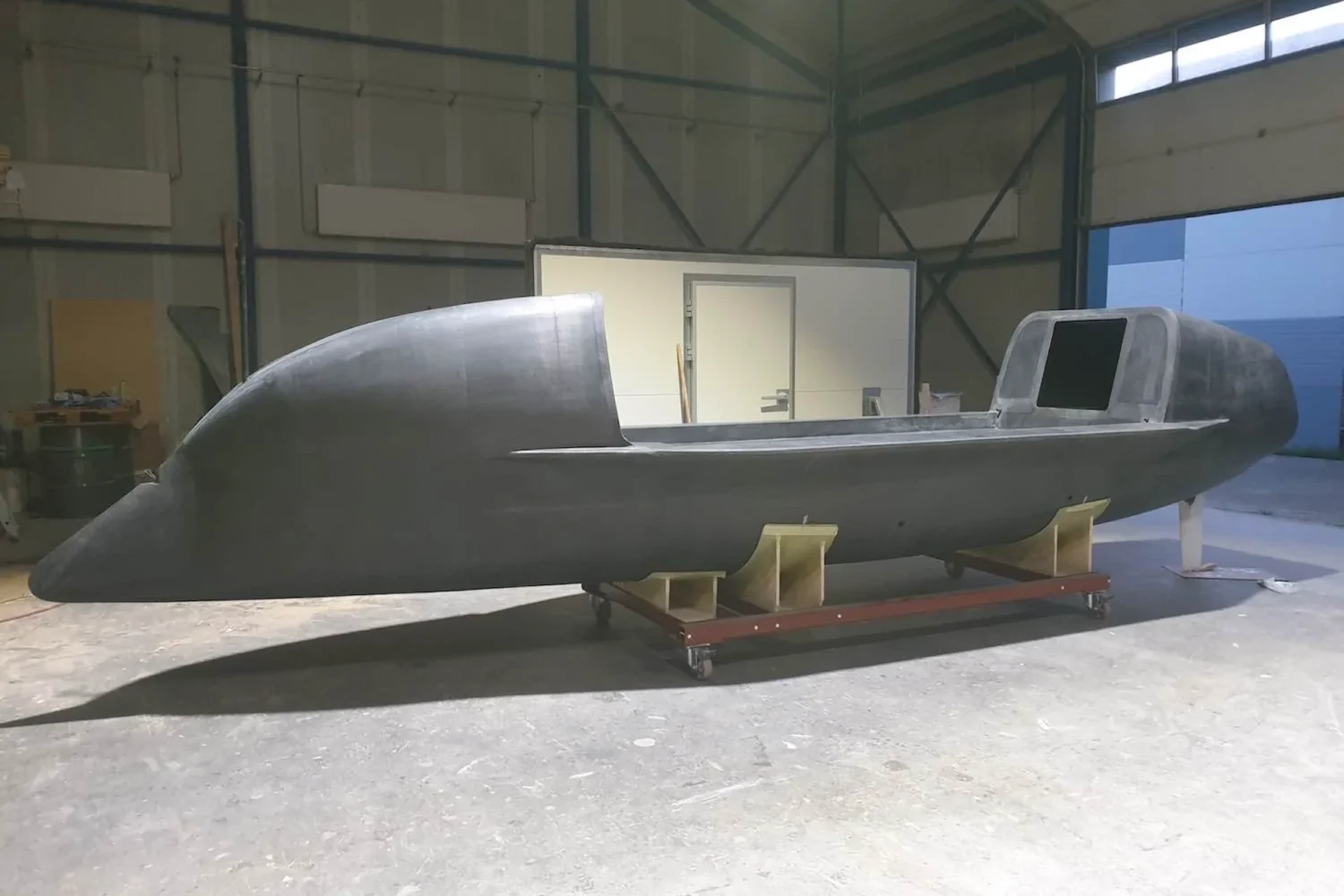 Ocean rowing boat on supports beside an open workshop door
