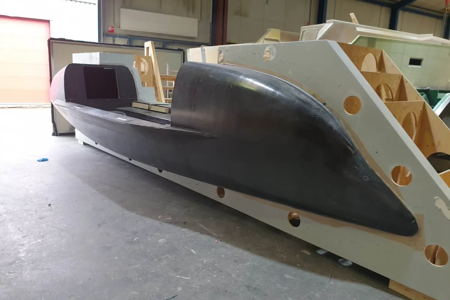 Dark ocean rowing boat with a light-coloured superstructure in the workshop