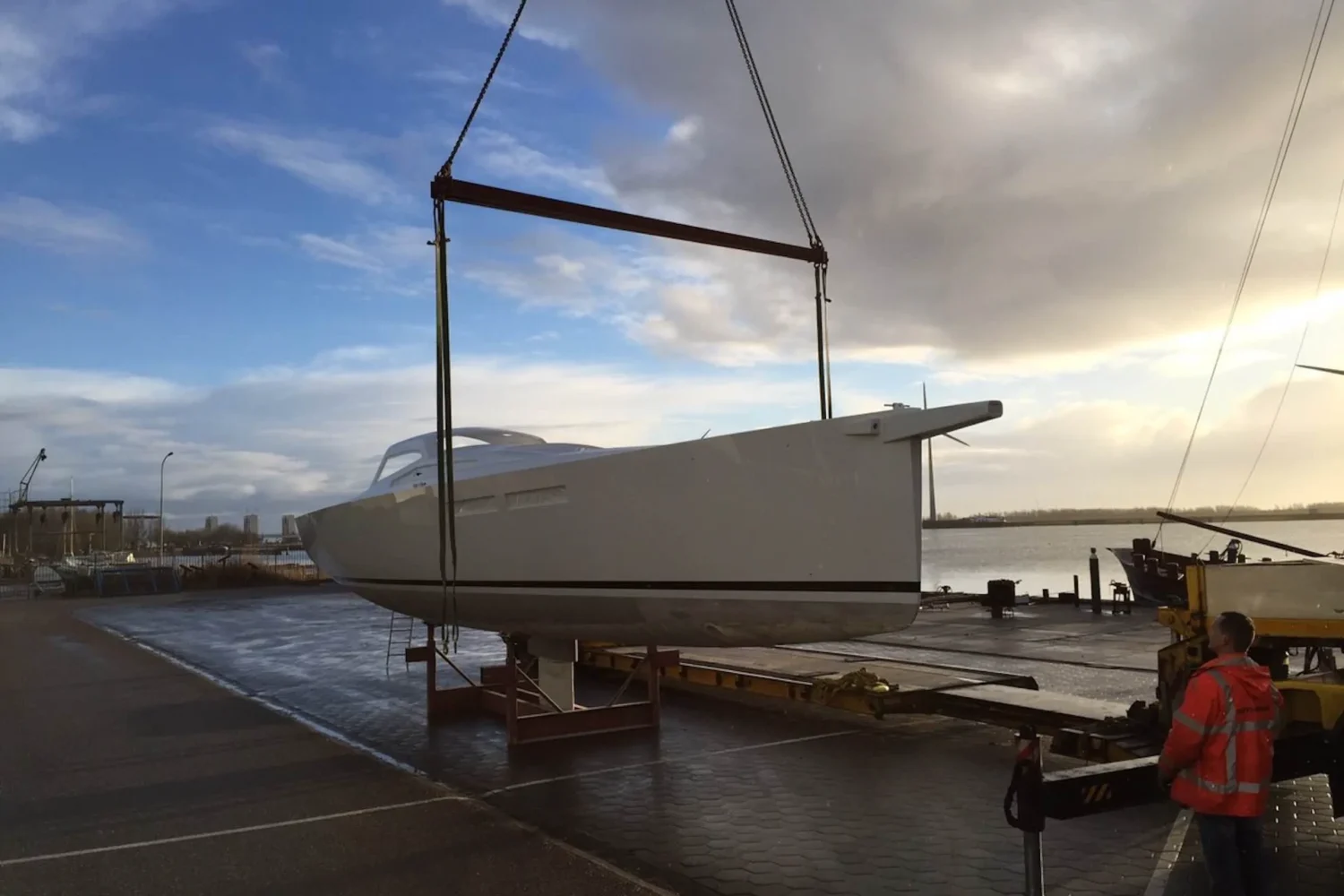 Boat hull suspended from a lifting beam above the quay
