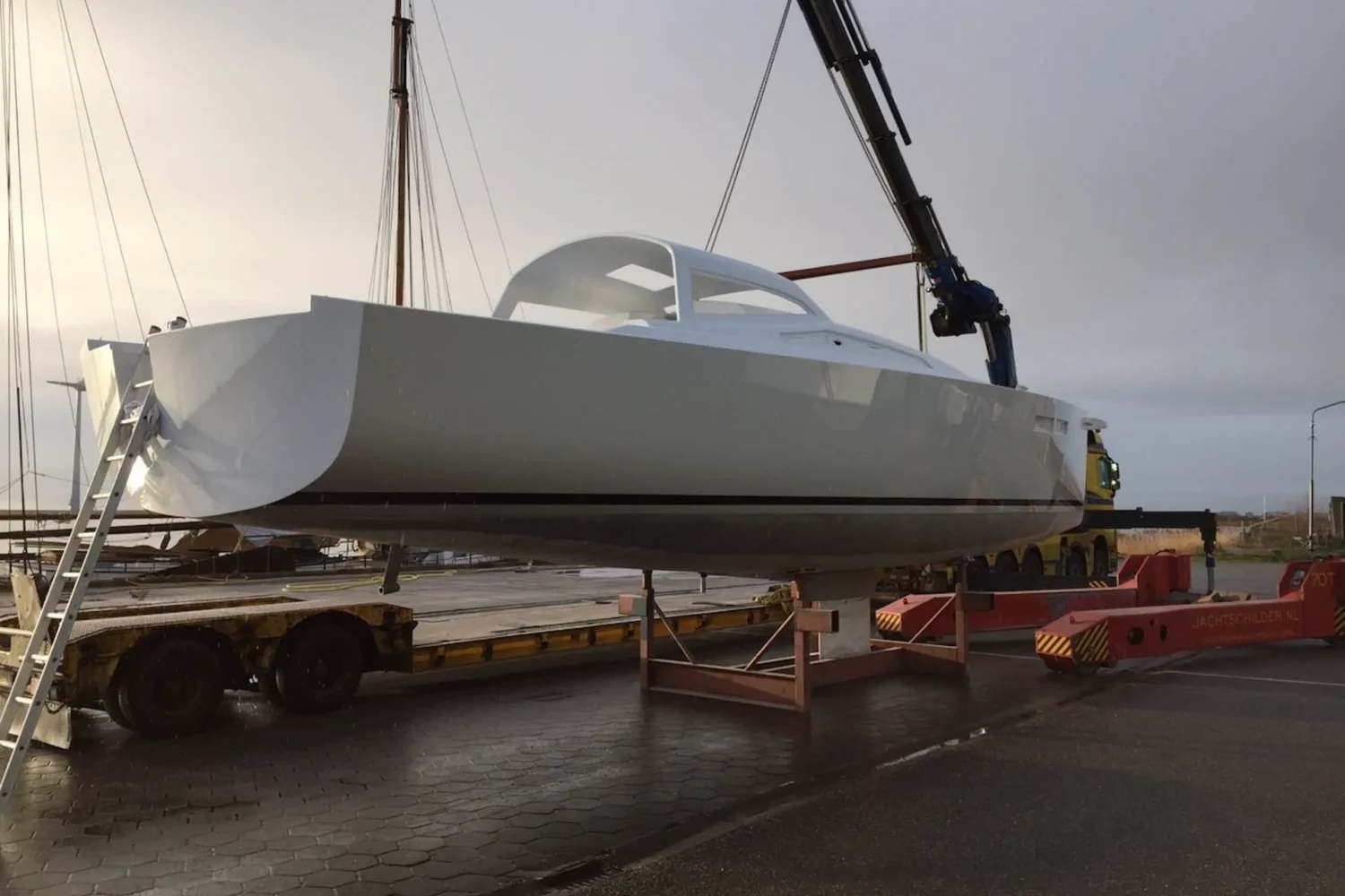 White boat hull on a crane at the quay