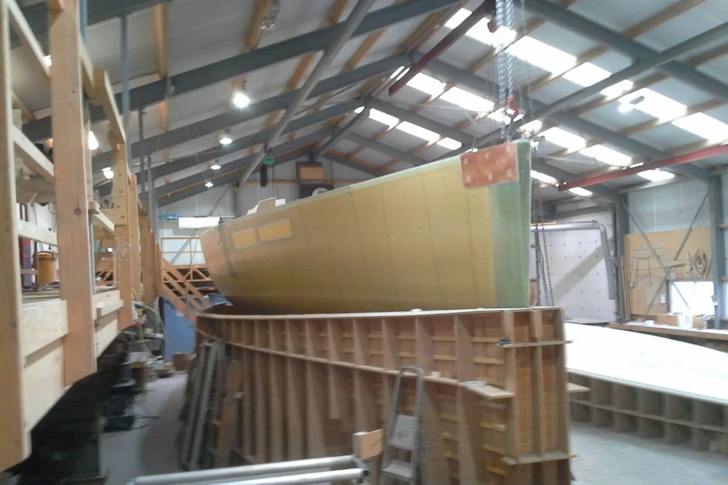 Boat hull being lifted above a wooden mould