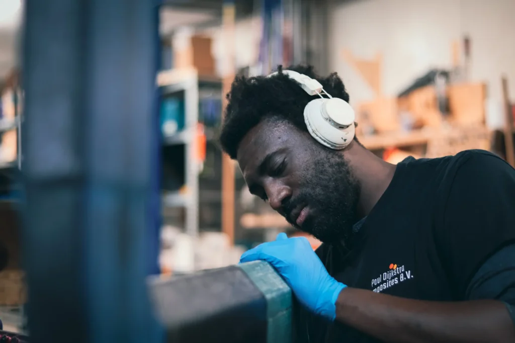 Een medewerker met gehoorbescherming werkt aan een composietonderdeel